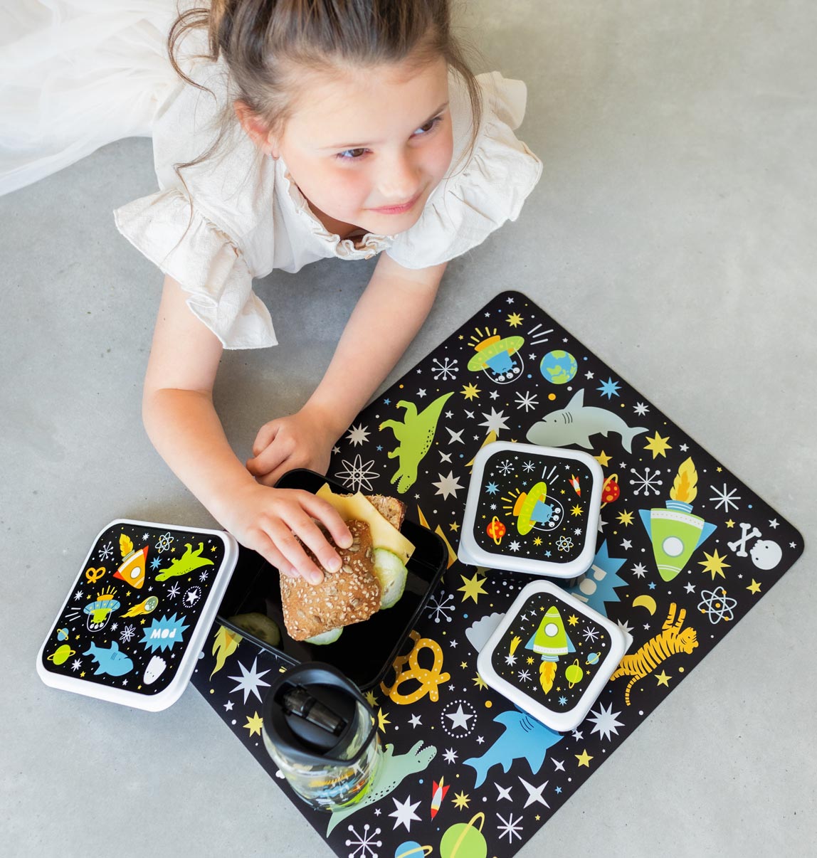 meisje dat broodje eet uit zwart broodbakje op bijpassende Galaxy placemat